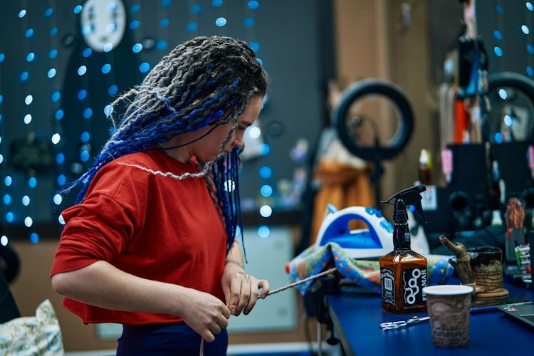 A Woman In Red Shirt Fixing A Synthetic Braid Hair