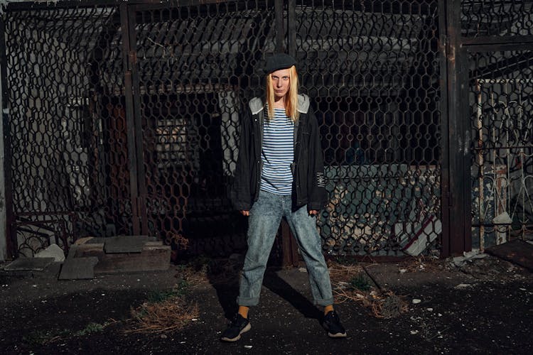 Young Woman Standing On The Background Of A Steel Fence 