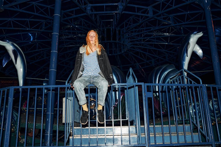 Redhead Girl In Leisure Clothing Sitting On Fence