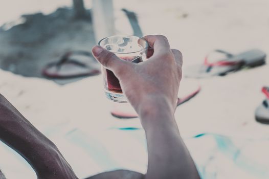 A person enjoying a drink on a sunny beach, capturing the essence of leisure and relaxation.