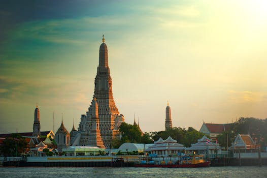 Stunning sunset view of Wat Arun temple by the Chao Phraya River in Bangkok, Thailand.