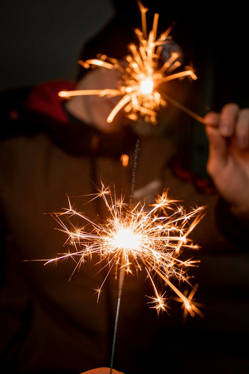 Free Person Holding Lighted Sparkler in Dark Room Stock Photo