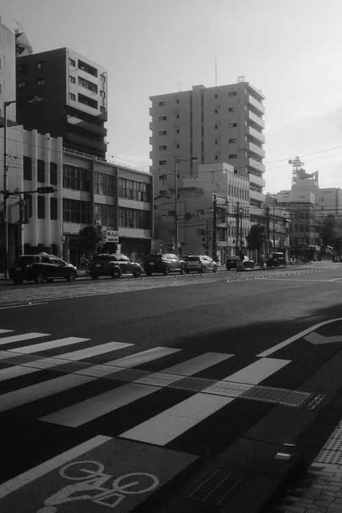 Free Monochrome cityscape featuring tall buildings and a busy road with zebra crossings. Stock Photo