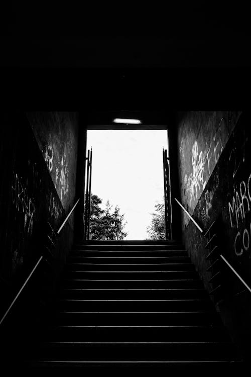 Grayscale Photo of Stairs in a Tunnel