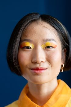 Vibrant portrait of a woman with bold makeup, smiling indoors.
