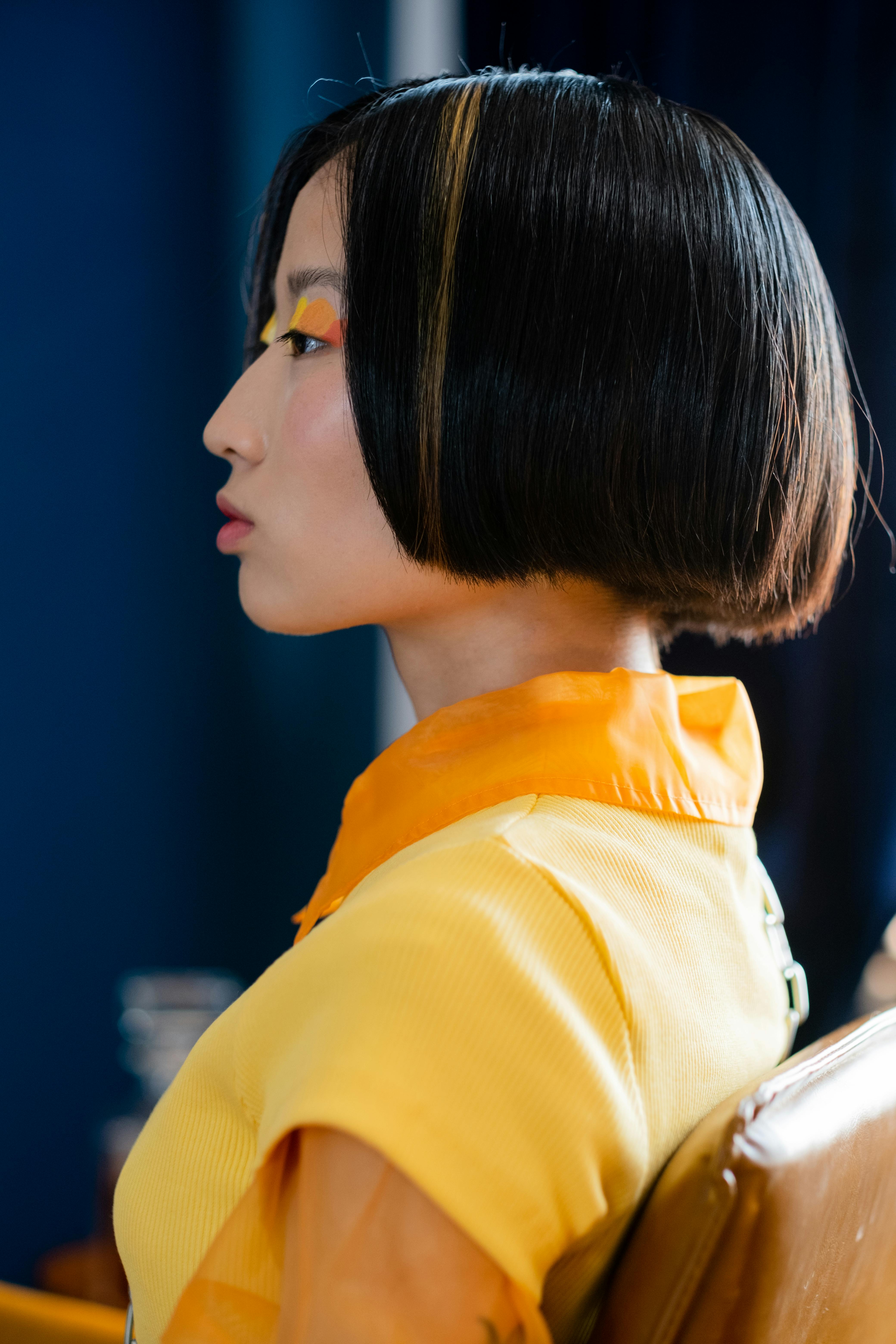 Profile of a woman with creative makeup and modern haircut in vibrant attire.