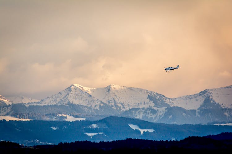 Helicopter Flying Above Winter Mountains On Sunset