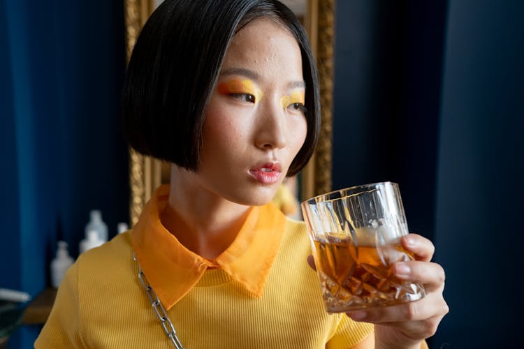 Woman Wearing Yellow Eyeshadow Drinking Whiskey