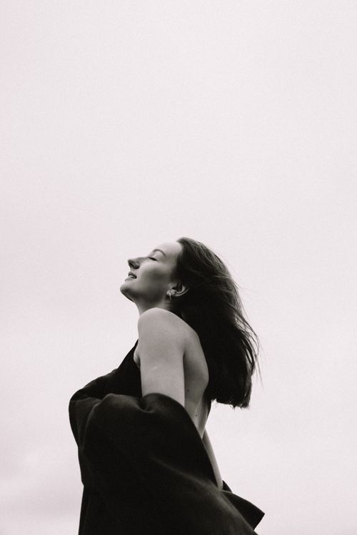 Free Black and white portrait of a woman with eyes closed enjoying a peaceful moment outdoors. Stock Photo