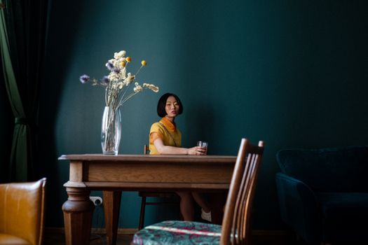 Woman Sitting by the Table and Holding a Glass