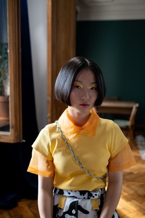 Free Portrait of a fashionable woman with a stylish haircut indoors, wearing a bright yellow top. Stock Photo