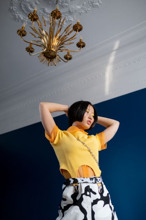 Free Stylish woman with short black hair posing under a decorative chandelier indoors. Stock Photo