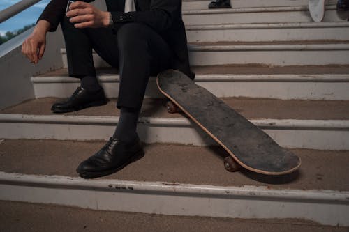 Photo of a Person's Legs Beside a Skateboard