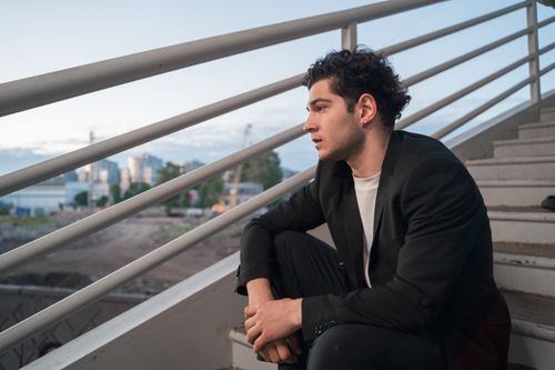 Free A young man in a blazer sitting on stairs outdoors during the day. Stock Photo