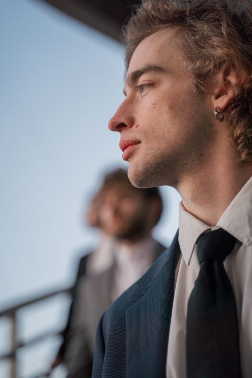 Free A close-up side profile portrait of a young man in a suit, with a blurred background. Stock Photo