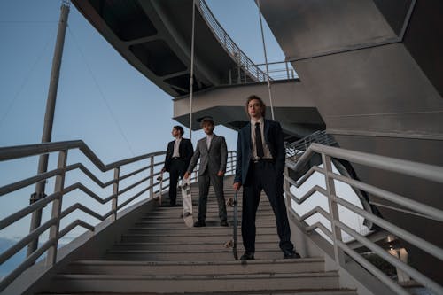 Three Men Standing on Metal Stairs