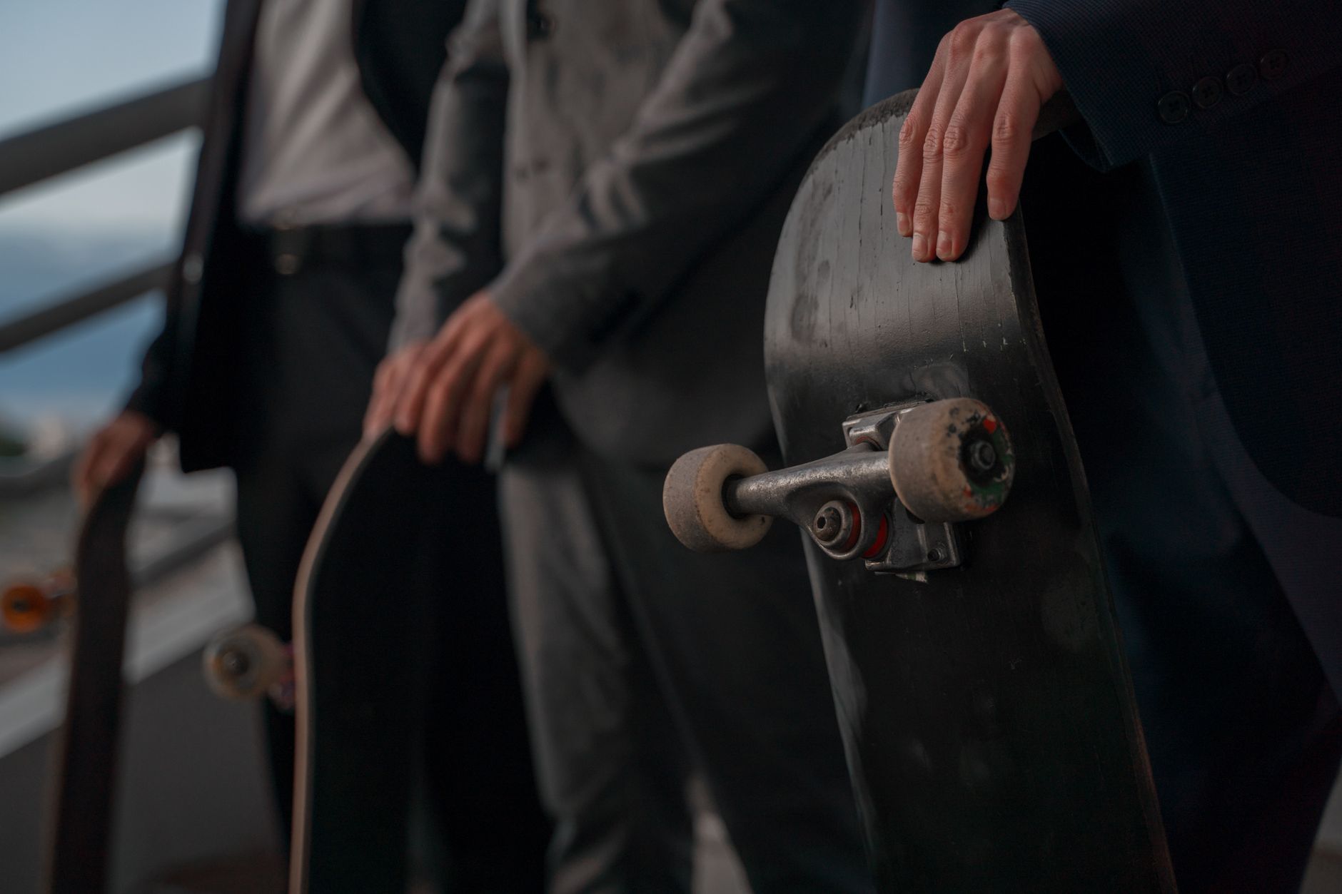Close-up of business professionals in suits holding skateboards, blending corporate and urban cultures.
