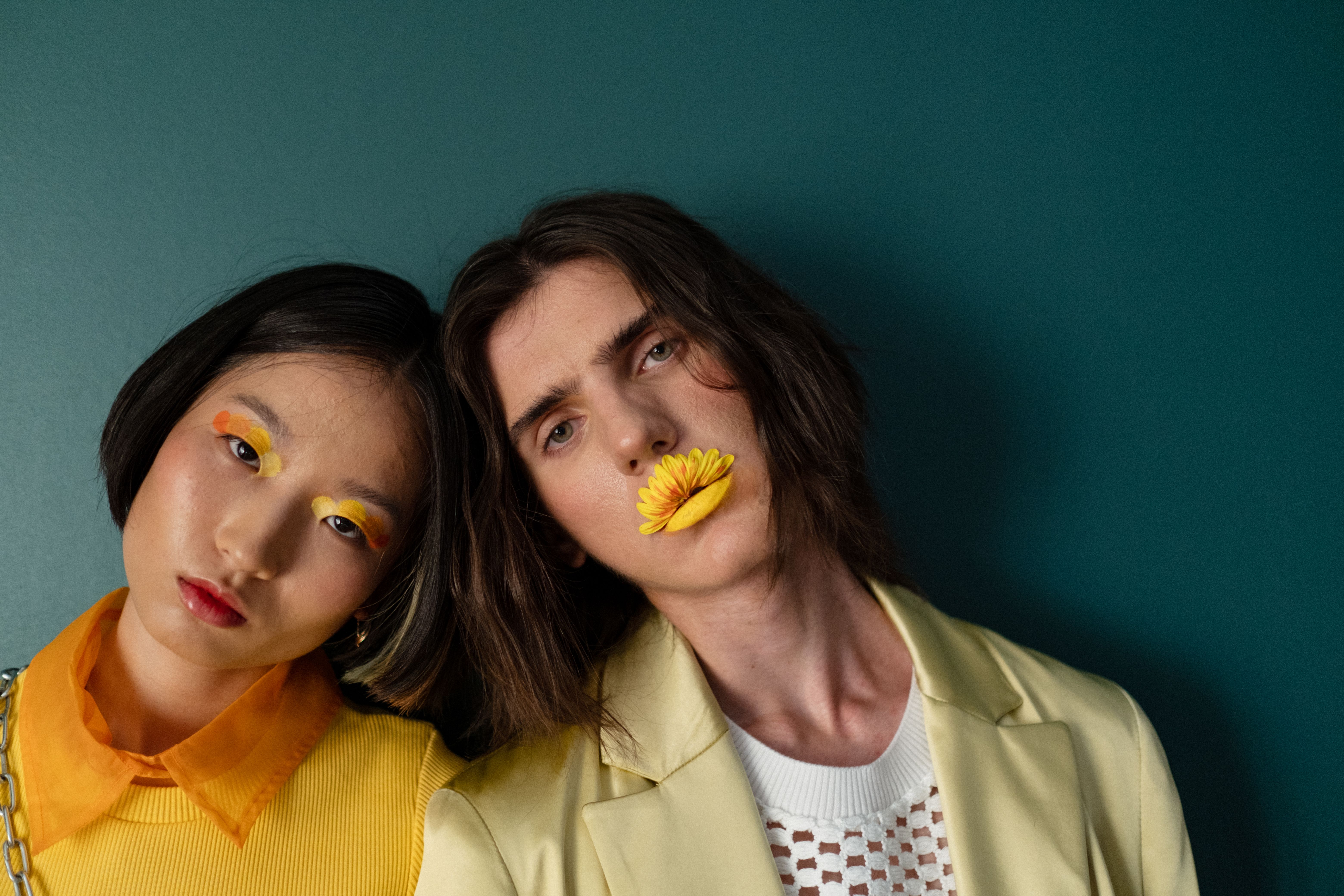 Artistic fashion portrait featuring diverse models with colorful makeup and unique styling.