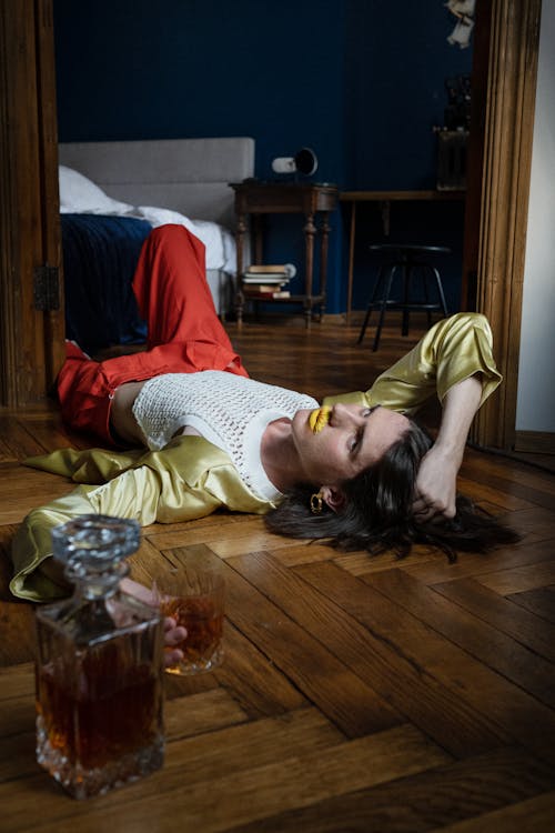 Man Laying in the Room on the Floor with Glass of Whiskey