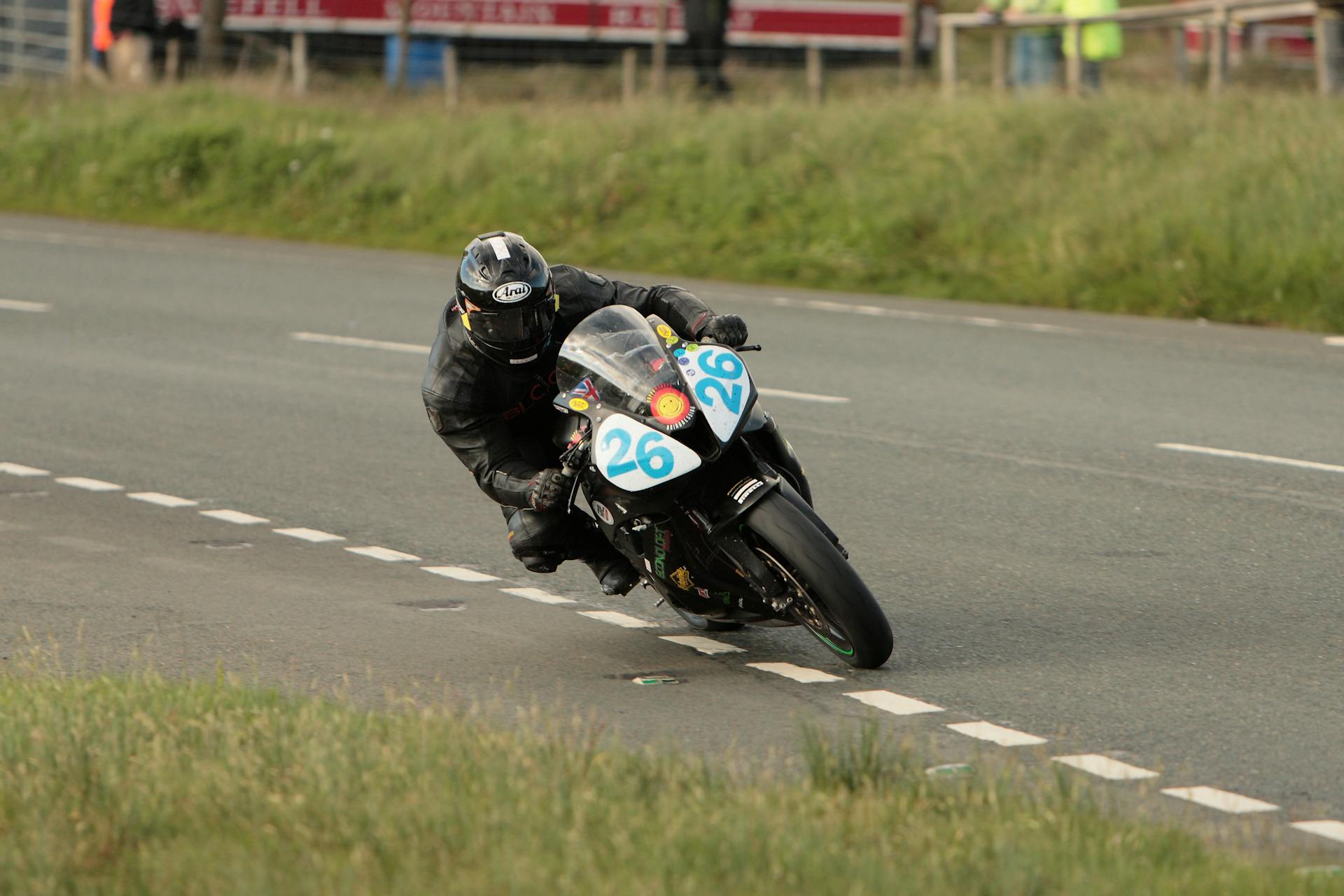 Intense motorcycle race captured on a rural Isle of Man road, showcasing speed and agility.