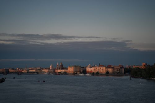 Free Tranquil evening view of city skyline with river reflecting sunset hues. Stock Photo