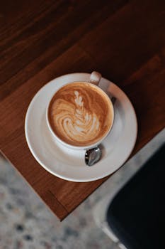 Captivating top view of latte art in a classic white cup on a wooden table.