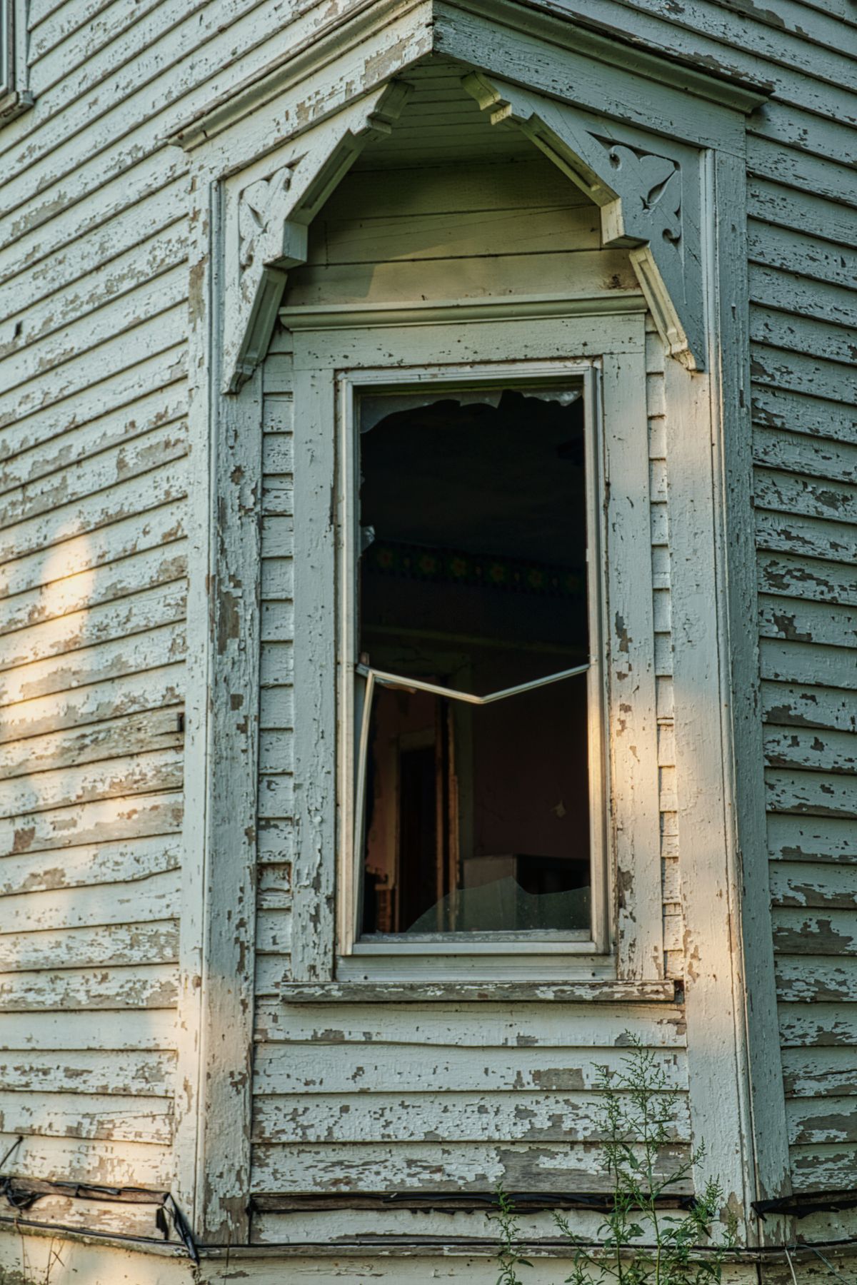 Peeling paint and a deteriorating window — deferred maintenance is often the first visible sign of a distressed property