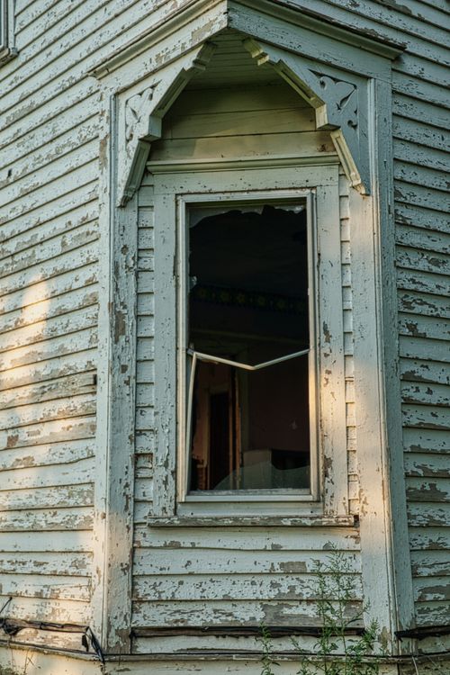 Free Close-up view of a deteriorating window on an old wooden building with cracked and peeling paint. Stock Photo