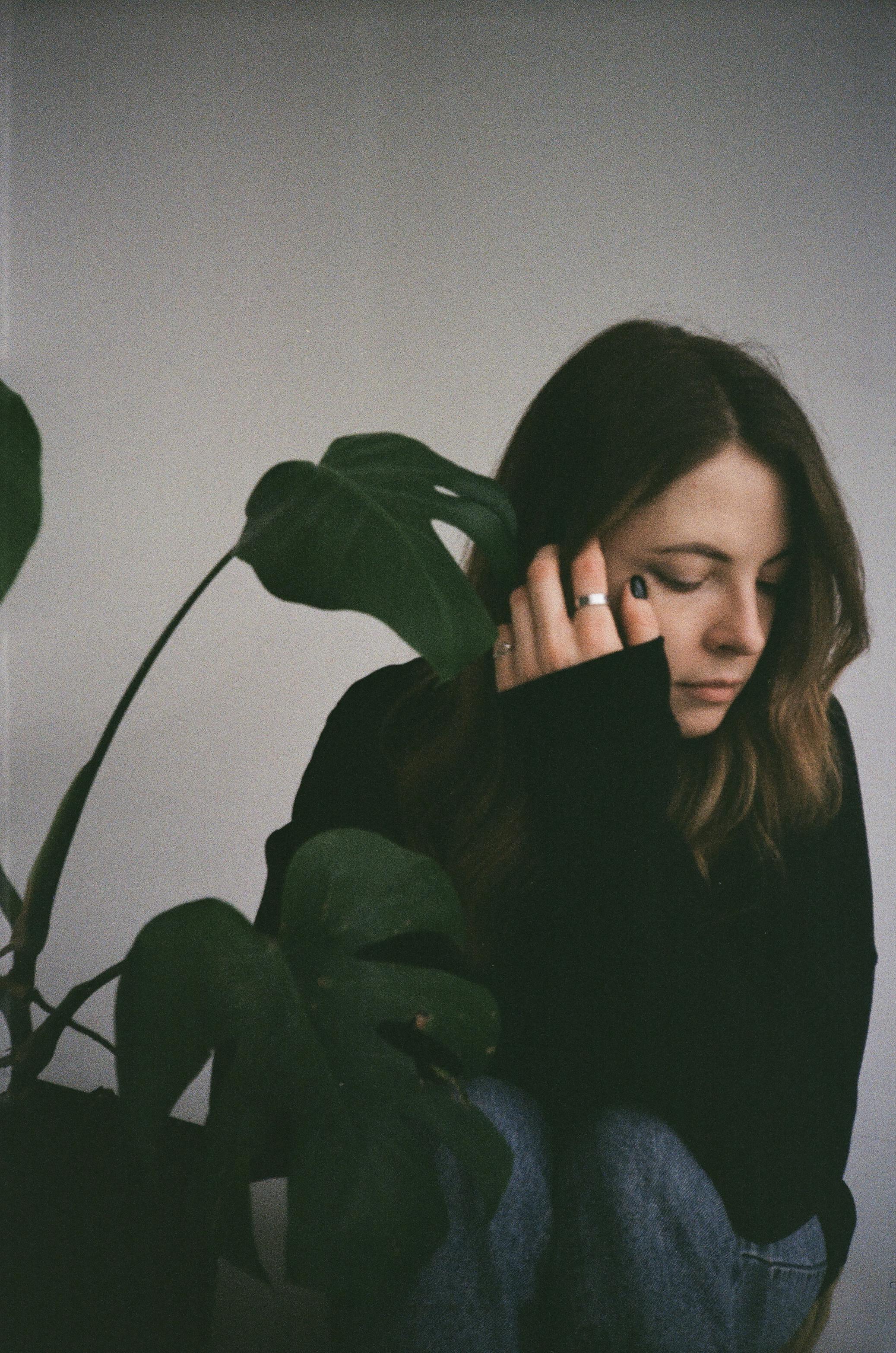 Free Photograph of a Woman Sitting Beside a Green Plant Stock Photo