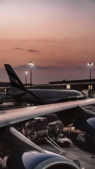 Beautiful view of airplanes parked at an airport terminal during sunset, showcasing aviation technology.