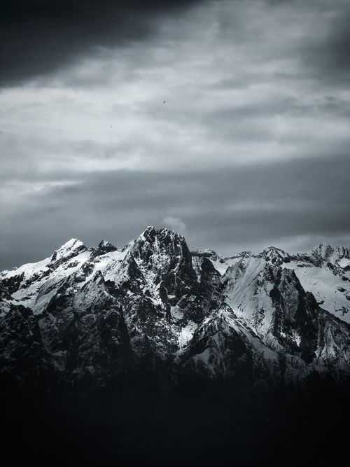 Free Majestic snow-covered mountains under a moody cloudy sky, offering a stunning and dramatic landscape view. Stock Photo