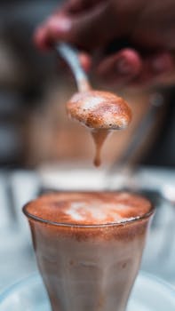 A detailed close-up of a frothy macchiato being prepared, highlighting rich coffee foam.