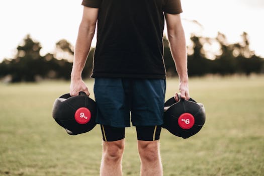 Man exercising outdoors with medicine balls in a park setting, promoting fitness and strength.