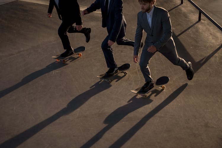 Photo Of Men In Suits Riding Their Skateboards