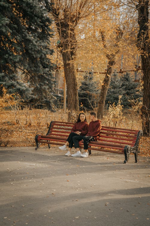 Free Photo of a Couple Sitting on a Brown Bench Stock Photo