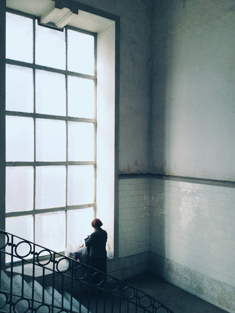 Woman Standing By Large Window