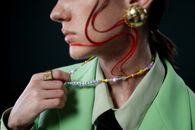 Androgynous Man Holding Necklace