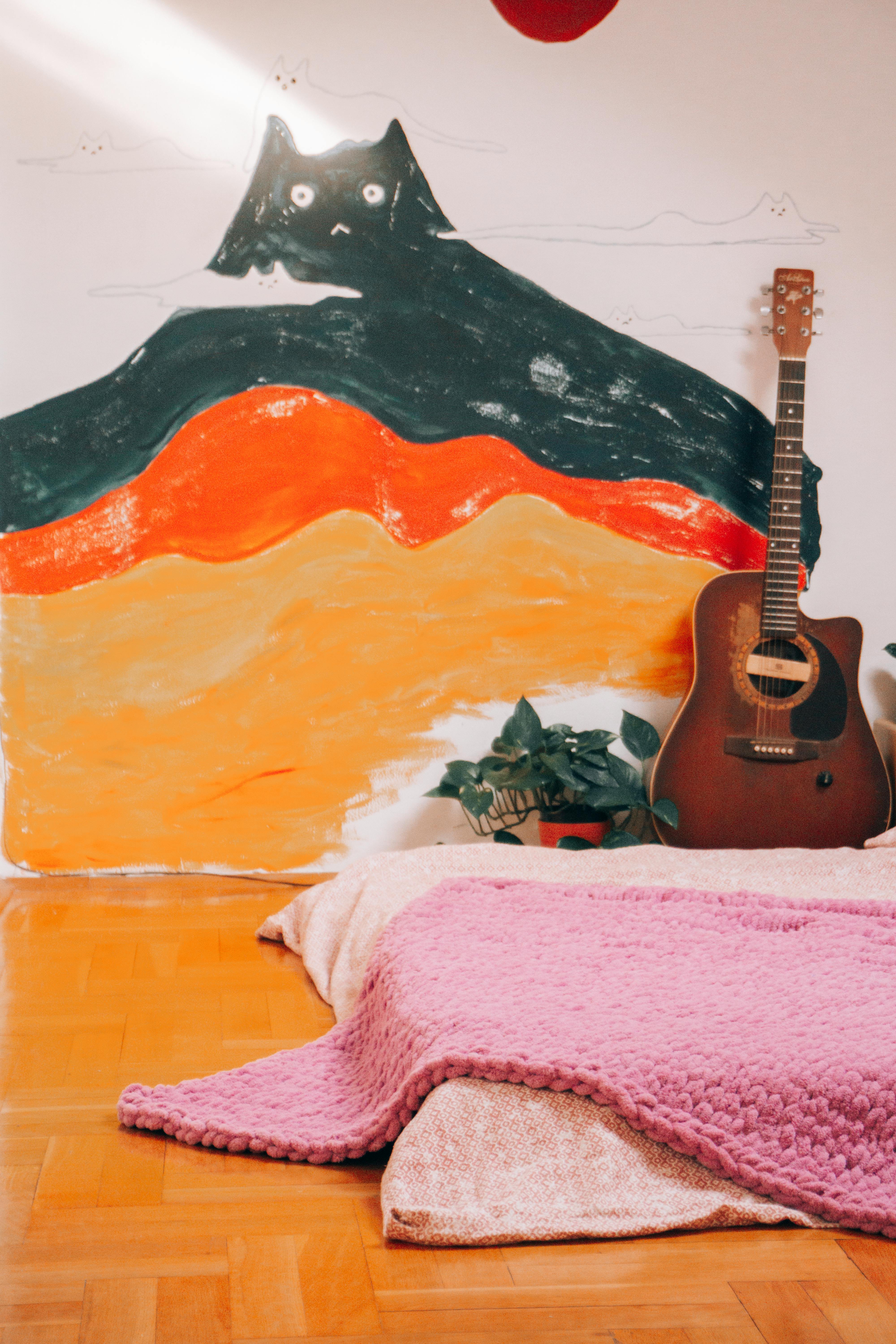 A warm interior featuring an acoustic guitar beside a vibrant cat mural, adding artistic flair.