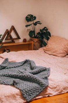 A cozy bedroom scene featuring plants, decor, and comfortable bedding.