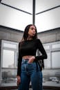 A Sexy Woman in Black Long Sleeves Crop Top and Denim Jeans Standing while Looking Afar