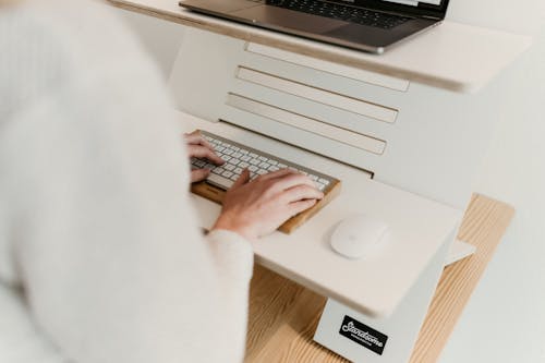 Photo of a Person Typing on a White and Silver Keyboard