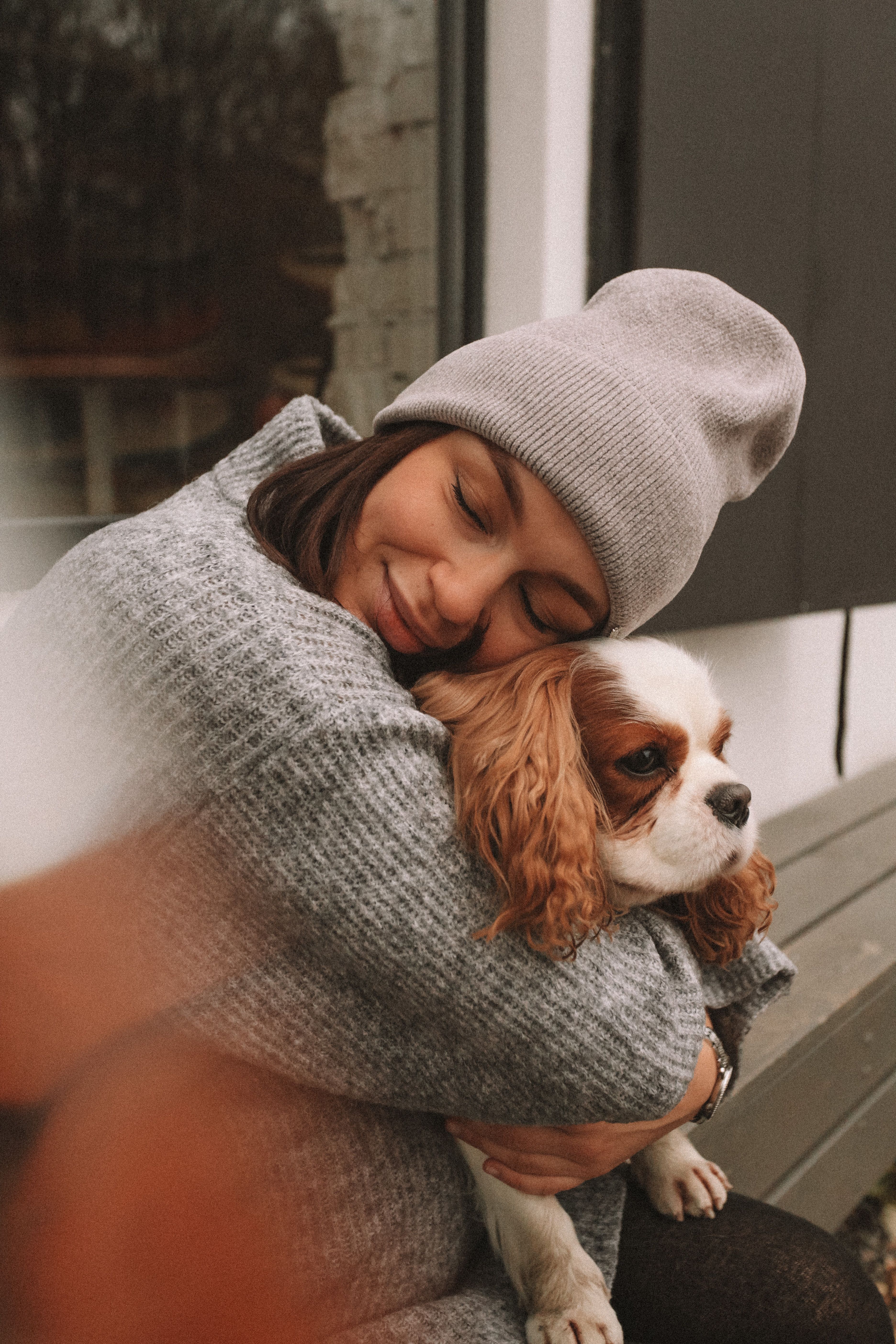 A woman hugging her beloved Cavalier King Charles Spaniel outdoors in authentic natural light.