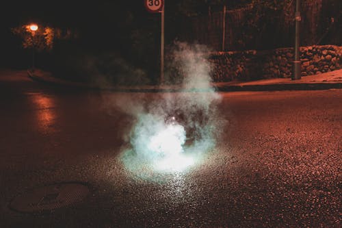 A Light and Smoke on a Dark Street at Night 
