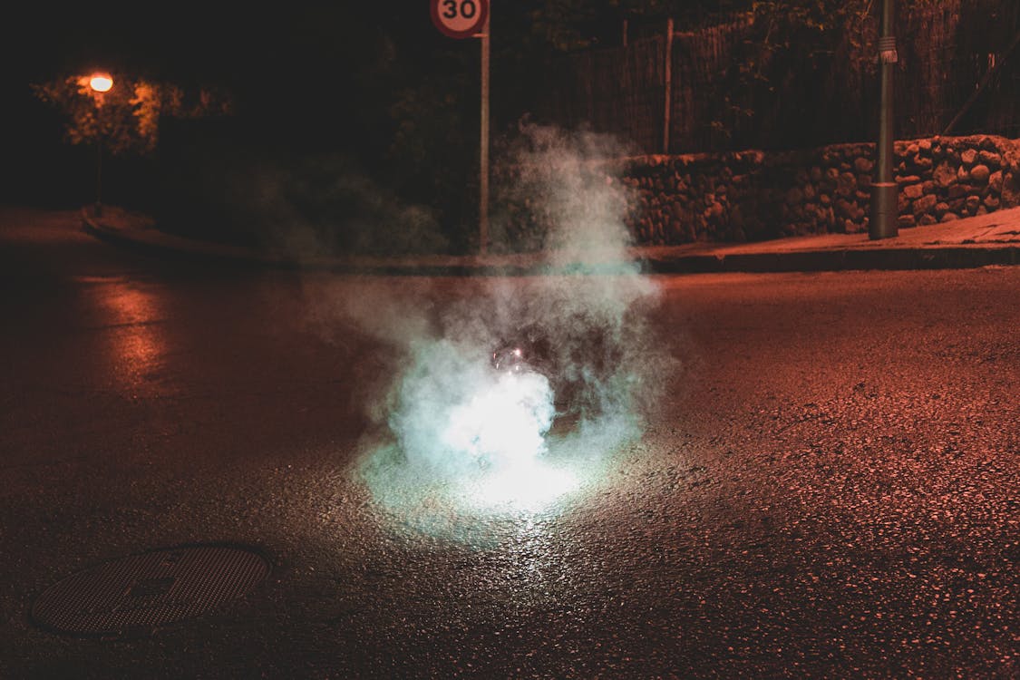 A Light and Smoke on a Dark Street at Night 