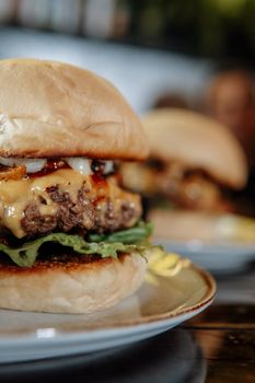 Close-up of a delicious cheeseburger with melted cheese and fresh lettuce on a ceramic plate.