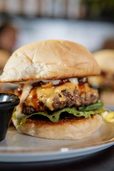 Close-up of a delicious cheeseburger with lettuce and sauce, showcasing food photography excellence.