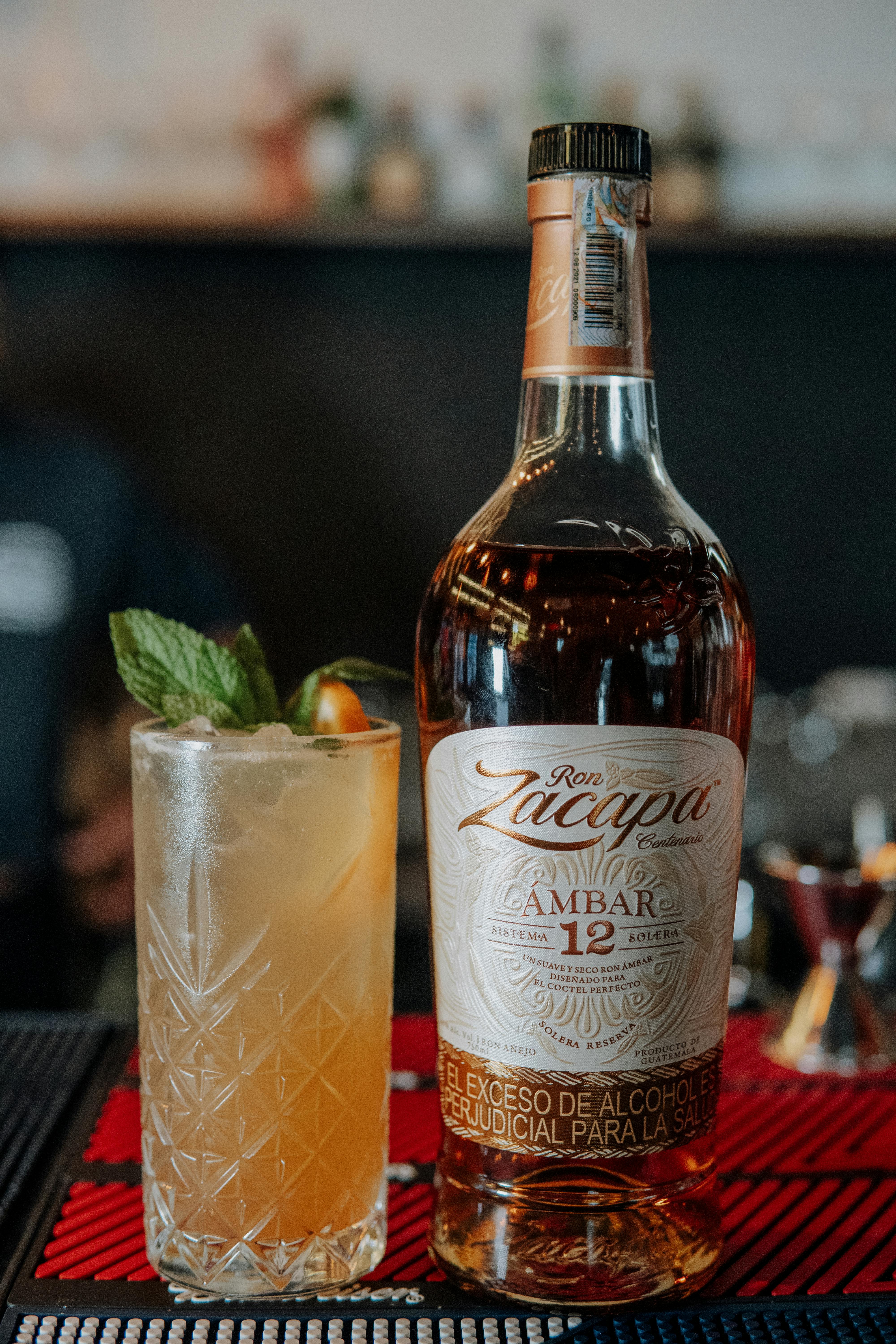 Elegant shot of premium rum and a cocktail with garnishes on a bar setting.