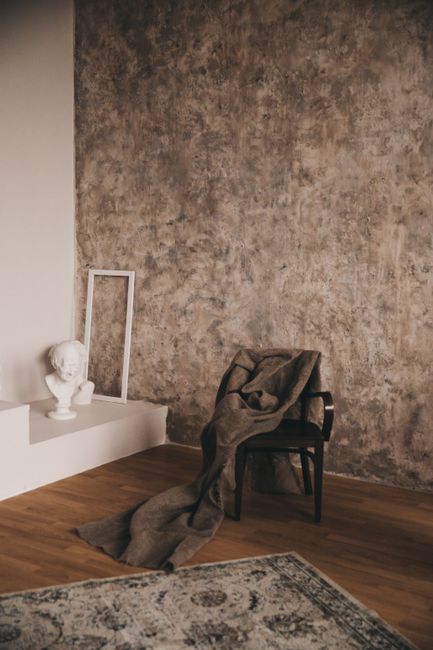 Rustic room featuring a chair with drapery, art bust, and textured wall.