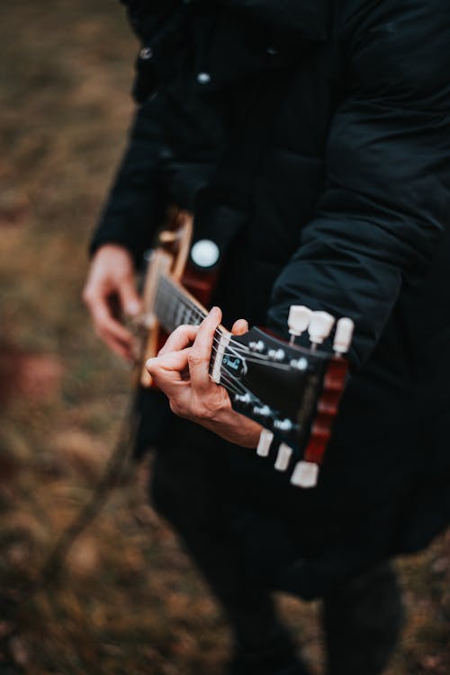 Free Person in a Black Jacket Playing a Guitar Stock Photo