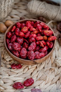 Close-up of vibrant red dried berries in a wooden bowl on woven placemat.